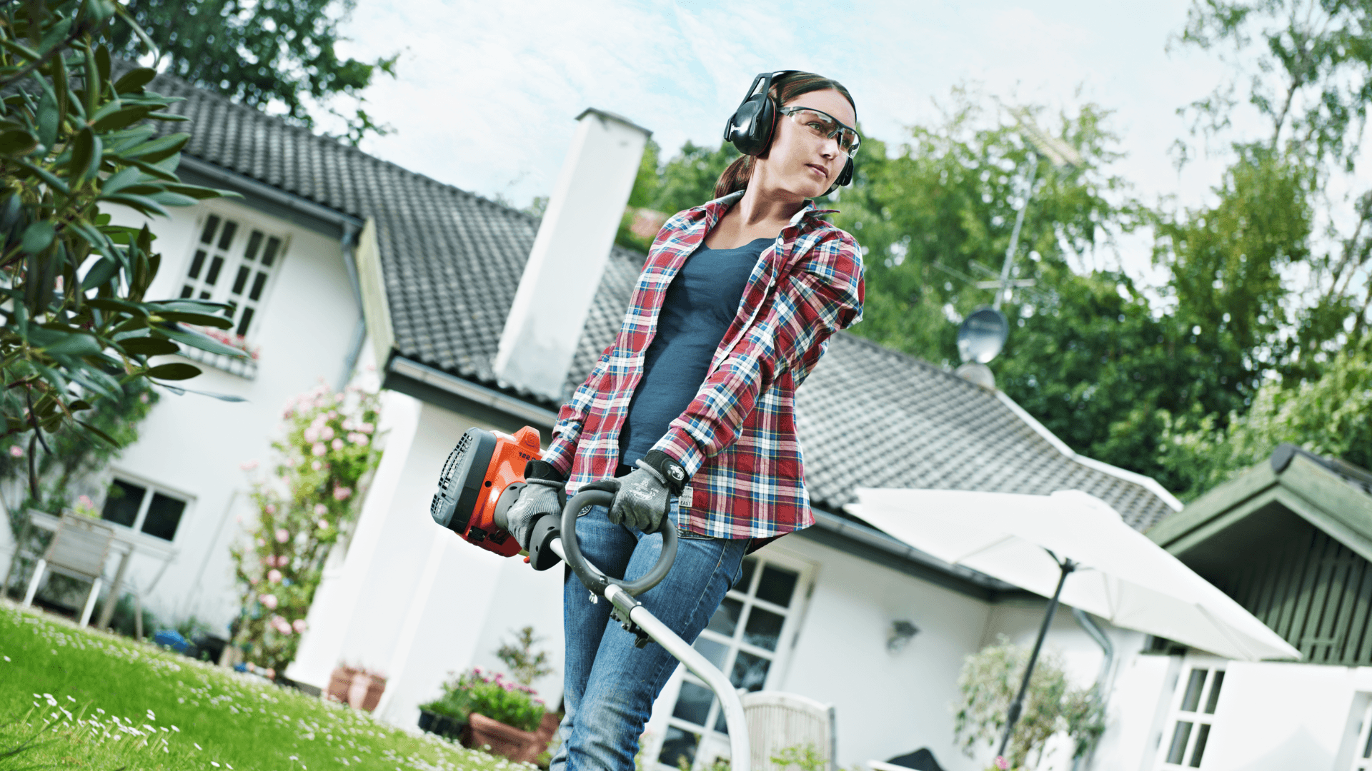 woman holding trimmer in her backyard